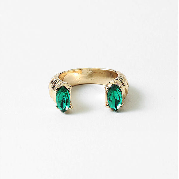 Gold ring with two green gemstones on a white background