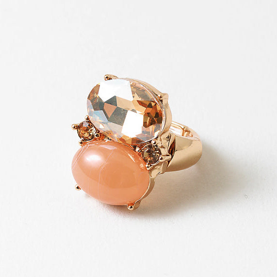 Gold ring with peach-colored gemstone on a white background