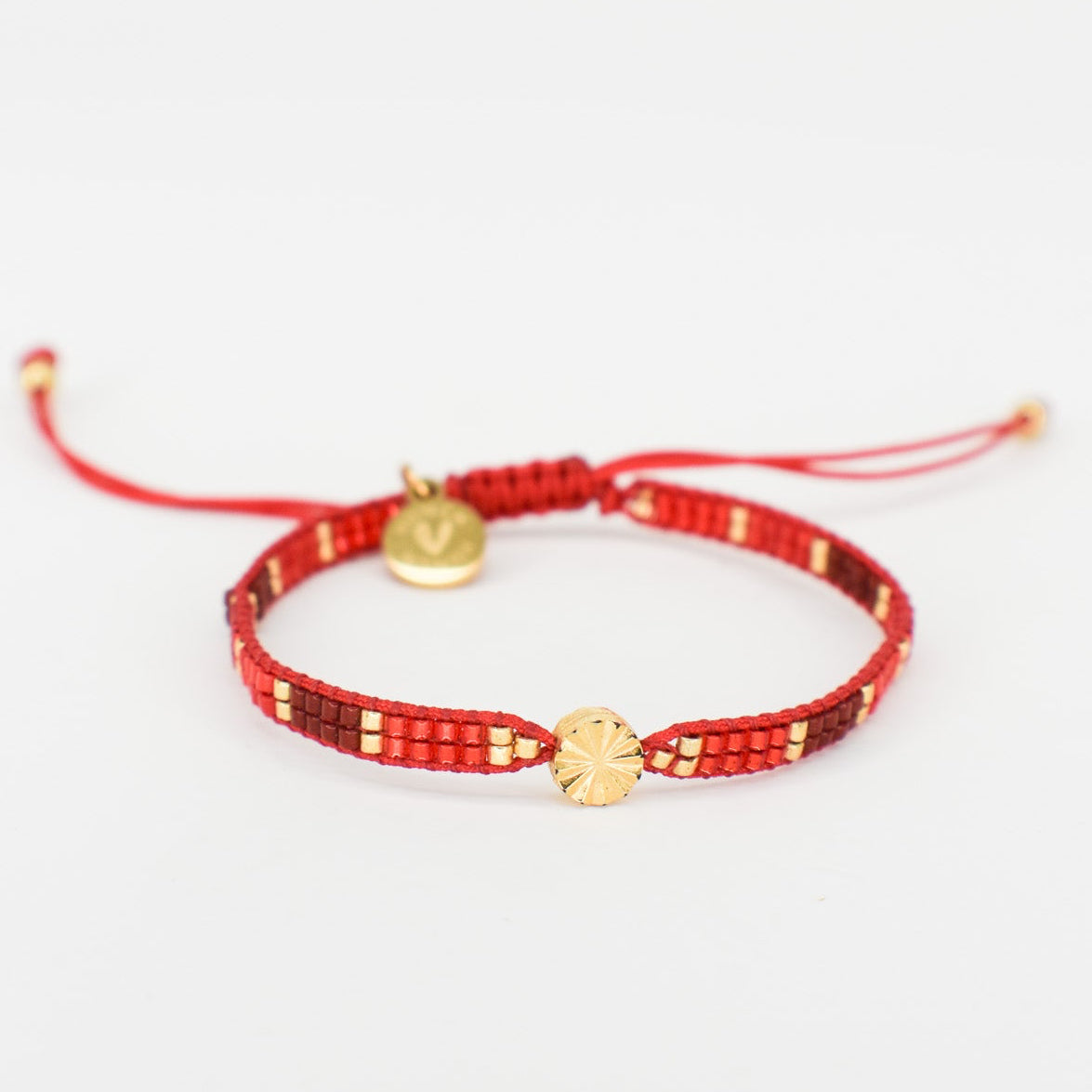 Red bracelet with gold charms on a white background