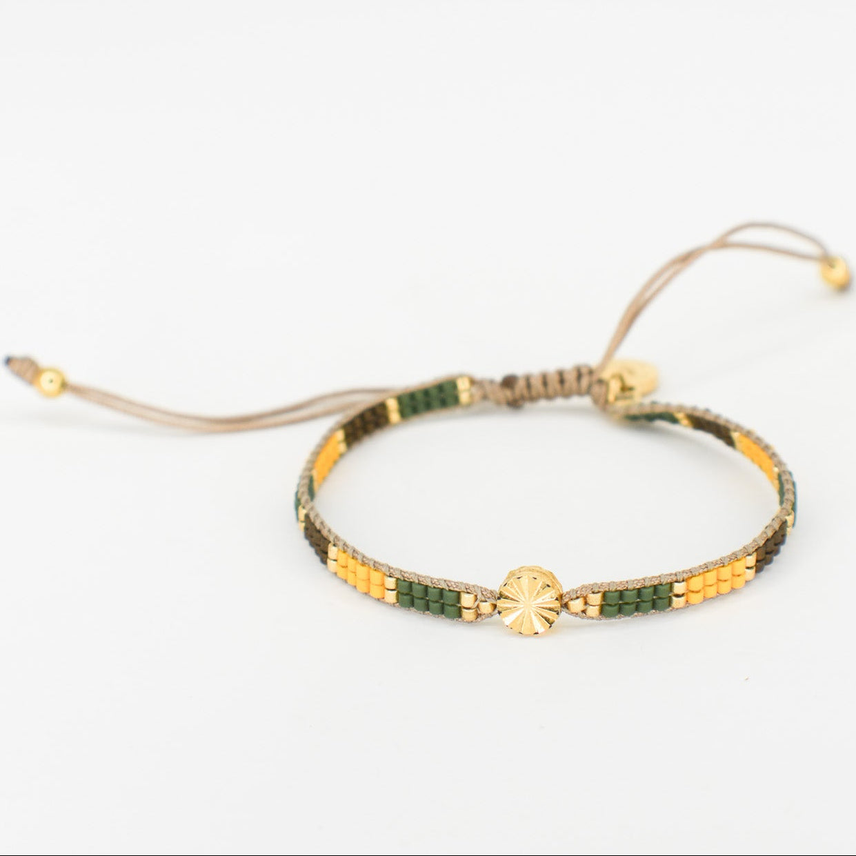 Bracelet with green and gold beads on a white background