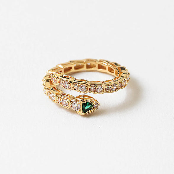 Gold snake-shaped ring with a green gemstone on a white background