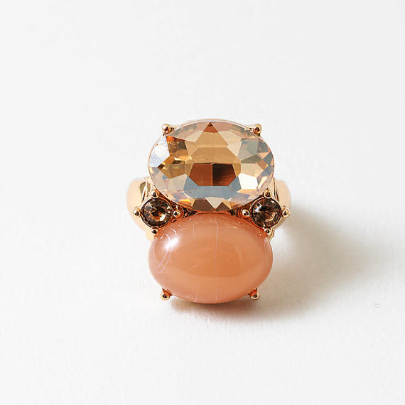 Ring with peach-colored gemstone and rose gold accents on a white background